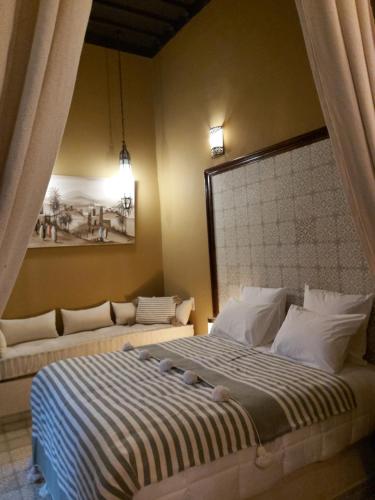 a bedroom with two beds and a painting on the wall at Riad Les Nuits de Marrakech in Marrakech