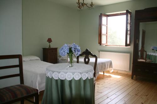 Una habitación con una mesa con un jarrón de flores. en Casa Pousadoira, en Miño