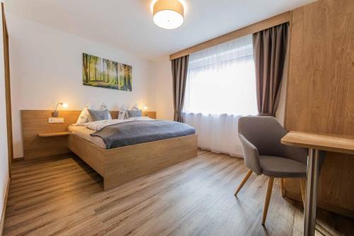um quarto com uma cama, uma secretária e uma janela em Berg' & Bluamen Appartements Stubai em Neustift im Stubaital