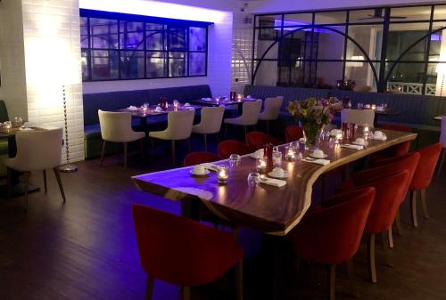 Hotel Ramor Garni في دويسبورغ: غرفة طعام مع طاولة طويلة وكراسي حمراء