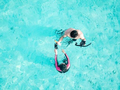two people in the water in a swimming pool at Nemo Inn in Omadhoo