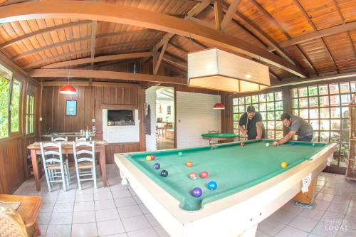 two people playing pool in a room with a pool table at Pousada Rosa in Praia do Rosa