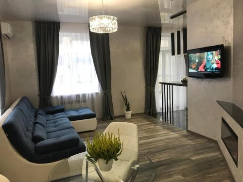 a living room with a blue couch and a tv at New luxury Apartment in the Center on Konstitution Square in Kharkiv