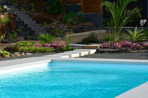 a swimming pool in a garden with a landscaping at Villa Coco Cannelle in Deshaies