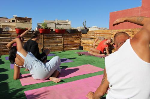 een groep mensen die yoga doen op een yogamat bij Sunset Surfhouse Morocco in Tamraght Ouzdar
