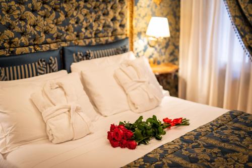 a hotel room with a bed with towels and roses at Hotel Santo Stefano in Venice