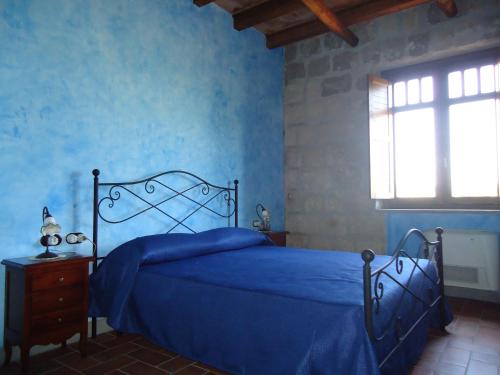 ein blaues Schlafzimmer mit einem Bett mit blauer Bettwäsche und einem Fenster in der Unterkunft Masseria Campierti in Falciano del Massico