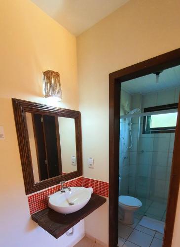 a bathroom with a sink and a mirror and a shower at Pousada Paraíso Gaia in Praia do Rosa