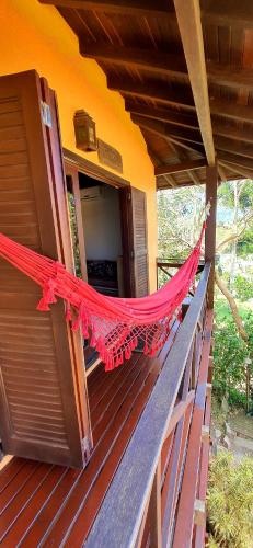 a red hammock on the porch of a house at Pousada Paraíso Gaia in Praia do Rosa