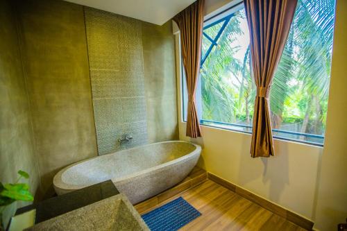 a bath tub in a bathroom with a large window at Moloppor Villa in Battambang
