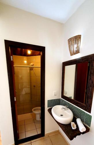 a bathroom with a sink and a toilet and a mirror at Pousada Paraíso Gaia in Praia do Rosa