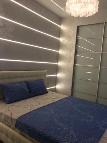 a bedroom with a bed with blue sheets and a chandelier at New luxury Apartment in the Center on Konstitution Square in Kharkiv