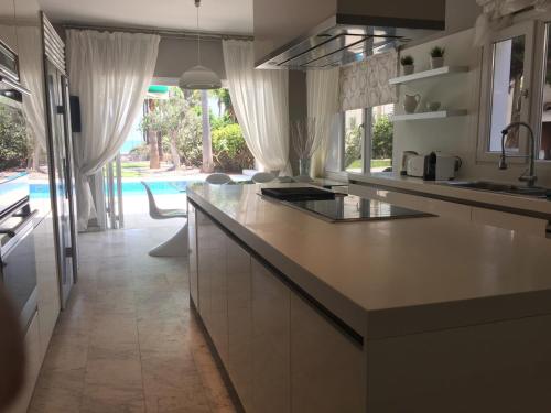 a kitchen with a counter and a pool in the background at Deluxe First Line Villa in Pervolia