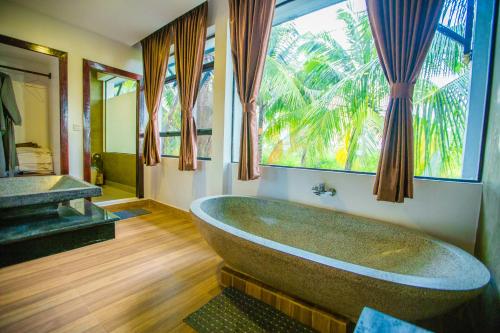 baño con bañera grande y ventana en Moloppor Villa, en Battambang