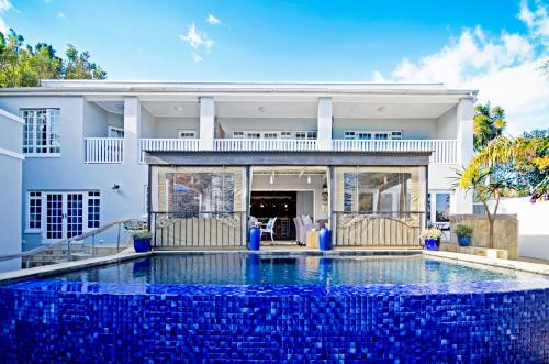 a house with a swimming pool in front of a house at Lodge on Main Guest House and Conference Centre in Port Elizabeth
