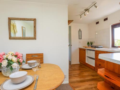 a kitchen with a wooden table with plates and flowers on it at Castell Chalet in Pwllheli