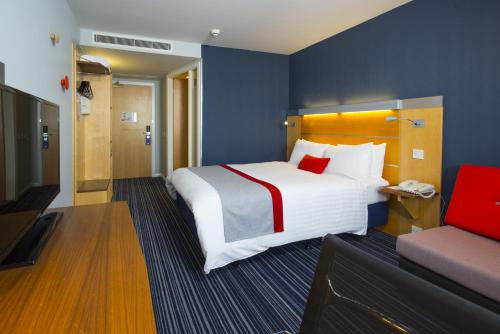 a hotel room with a large bed and a chair at Holiday Inn Express London - Epsom Downs by IHG in Epsom