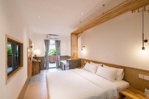 a bedroom with a white bed and a television at Zen Tea House Seven Stars Park in Guilin