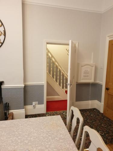 a dining room with a table and a staircase at Hargate Hall Self Catering in Buxton