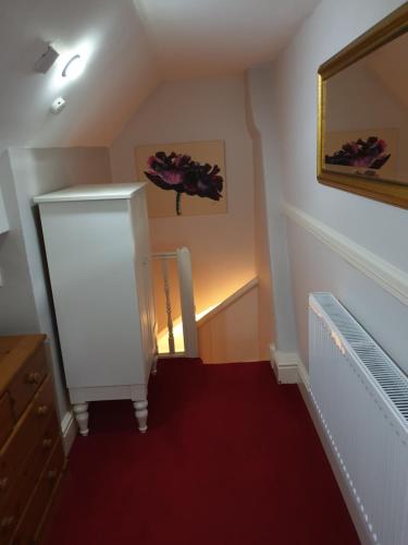 a hallway with a staircase with a mirror and red carpet at Hargate Hall Self Catering in Buxton