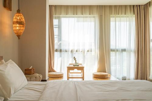 a bedroom with a white bed and a window at Zen Tea House Seven Stars Park in Guilin