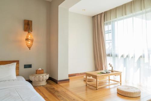 a bedroom with a bed and a table and a window at Zen Tea House Seven Stars Park in Guilin