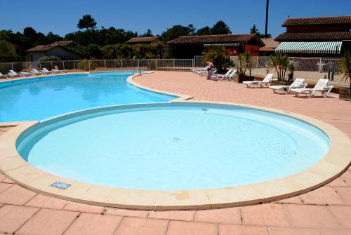 a large swimming pool with chairs in a resort at Résidence Néméa Les Rives de Saint Brice in Arès