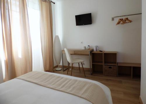 a bedroom with a bed and a desk with a television at Les Hauts de Malirat in Capdenac-Gare