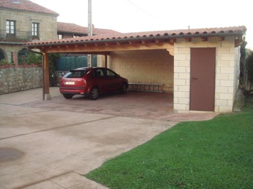 a car parked under a garage with a roof at Apartamentos Rurales Los Solares in Mogro