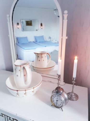 a room with a bed and a mirror and a clock at Höhällets Lantliga Rum in Värnamo