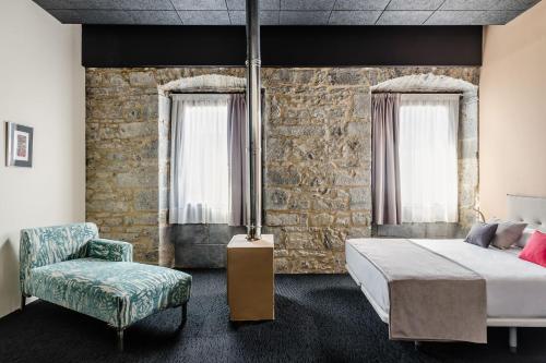 um quarto com uma cama e uma cadeira em Hotel Balneario Orduña Plaza em Orduña