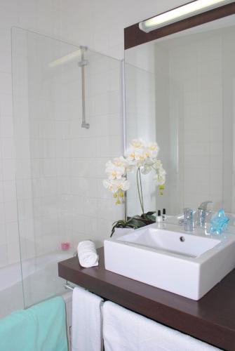 une salle de bain avec un lavabo blanc et un miroir dans l'établissement Résidence Néméa Les Terrasses de l'Océan, à Moliets-et-Maa