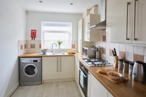 a kitchen with a sink and a washing machine at Ropers Retreat in Queensbury