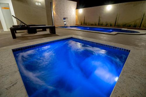 una gran piscina con iluminación azul en una habitación en Pousada Recanto das Caldas, en Caldas Novas
