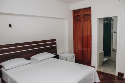 a bedroom with a white bed and a wooden headboard at SAMIR HOTEL COMFORT in Porto Velho