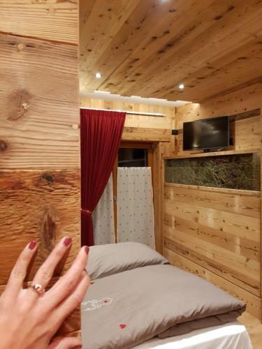 a person with their hand on a bed in a room at AGRITURISMO La Giasena in Ponte nellʼAlpi