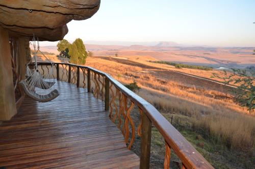 a wooden walkway with a hammock on the side at Antbear Eco Lodge Drakensberg in Emhubeni