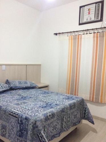 a bedroom with a bed with a blue comforter at RESIDENCIAL ANNABEL APTO 03 in Bombinhas