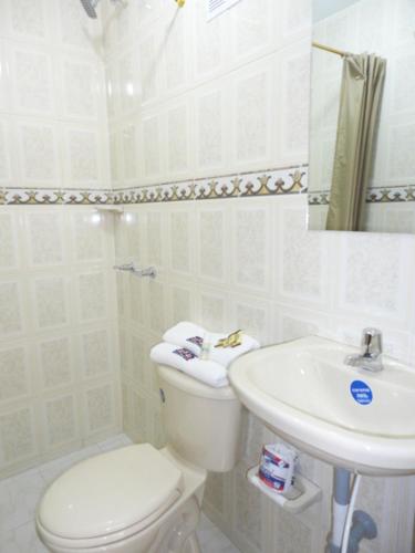 a white bathroom with a toilet and a sink at Hotel Casa Guillermo in Bogotá