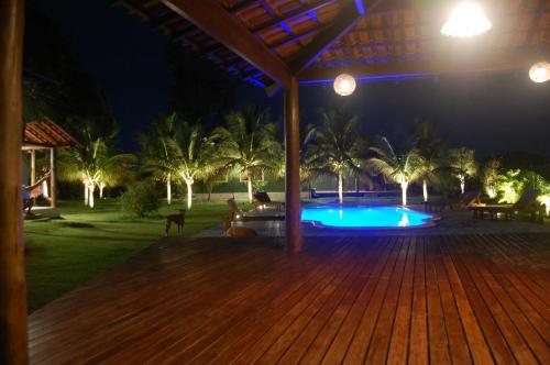 a wooden deck with a pool at night at Mangaba Village in Barra Grande