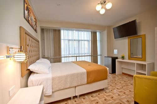 um quarto de hotel com uma cama e uma televisão em Mercé Hotel em Tacna