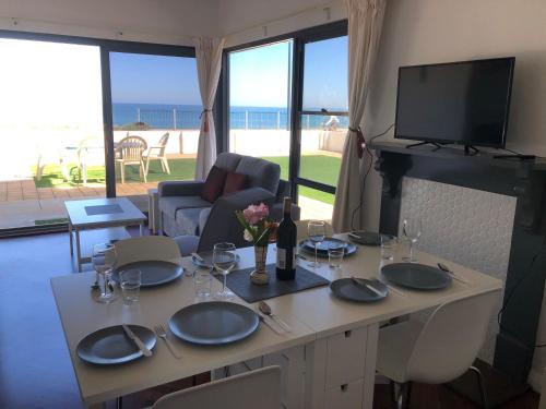 a dining table with plates and glasses and a view of the beach at The Somerton Beach Retreat in Somerton Park