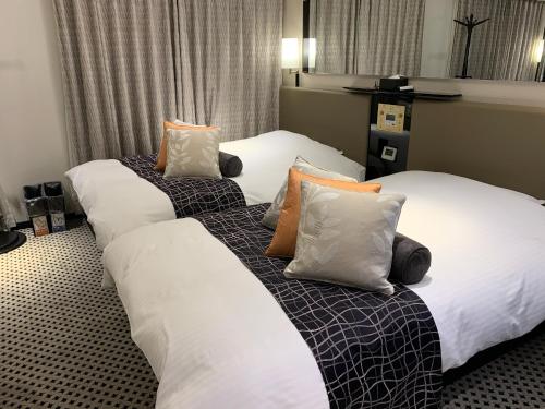 dos camas sentadas una al lado de la otra en una habitación de hotel en APA Hotel TKP Keikyu Kawasaki Ekimae, en Kawasaki