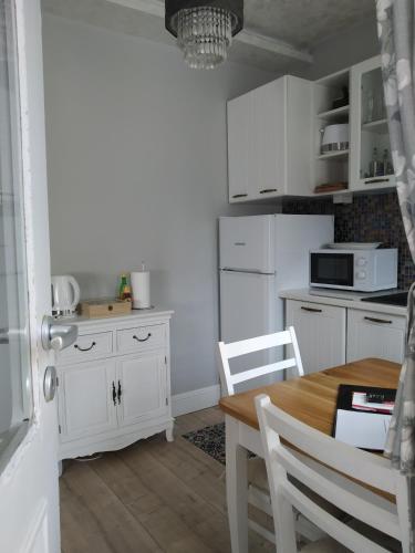 a kitchen with white cabinets and a table and chairs at My Home, with free secure parking in Stara Zagora