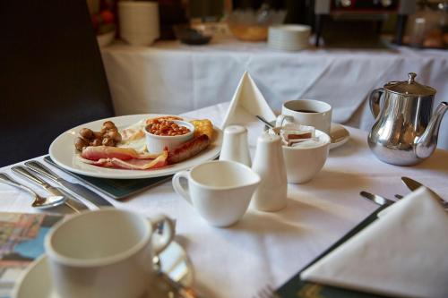 a table with a plate of food and cups on it at Best Western The George Hotel, Swaffham in Swaffham