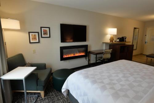 a hotel room with a bed and a fireplace at Holiday Inn Hotel & Suites Minneapolis-Lakeville by IHG in Lakeville