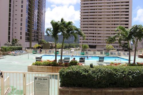 a swimming pool with palm trees and buildings at PonoAloha in Honolulu