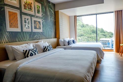 two beds in a hotel room with a large window at Panan Krabi Resort in Ao Nang Beach