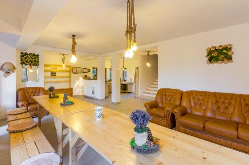 a living room with a wooden table and leather furniture at Agropensiunea Mara in Mărişel