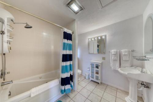 a white bathroom with a tub and a sink and a bath tub at Magnolia House in Butler Beach